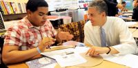 P-TECH student and mentor discussing a project that has been drawn into a paper.